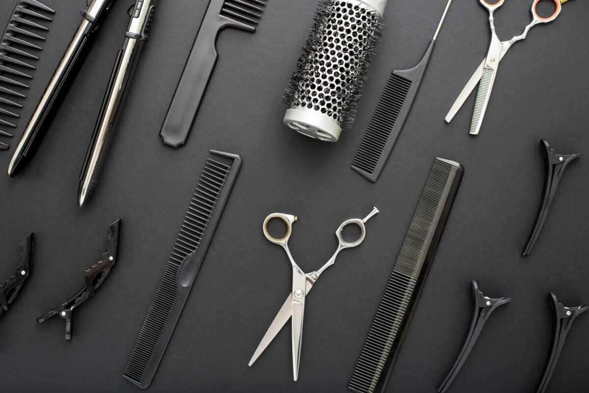 Flat lay composition with Hairdresser tools: scissors, combs, hair iron on black background with copy space for text. Hairdresser service. Beauty salon service. Hairdresser Set